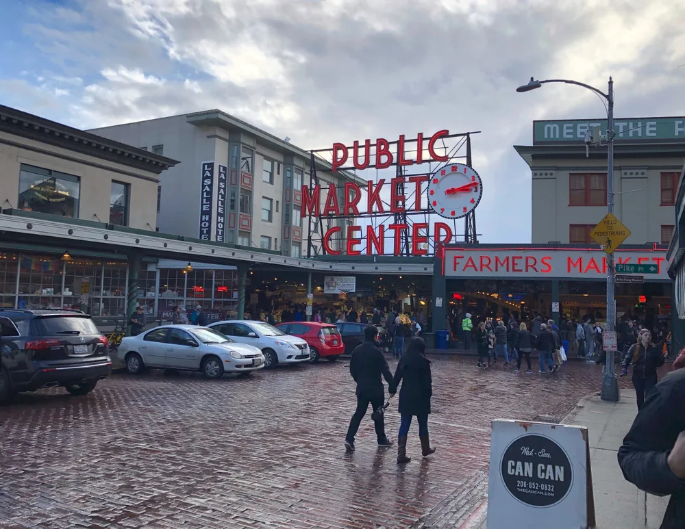 Photo of people walking along and holding hands in Pike Place Market during winter, the cheapest time to visit Seattle
