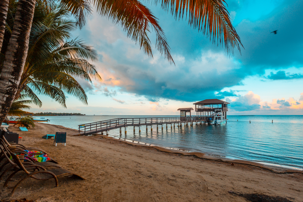Empty Sandy Bay Beach pictured below cloudy skies on Roatan, seen during the least expensive time to visit