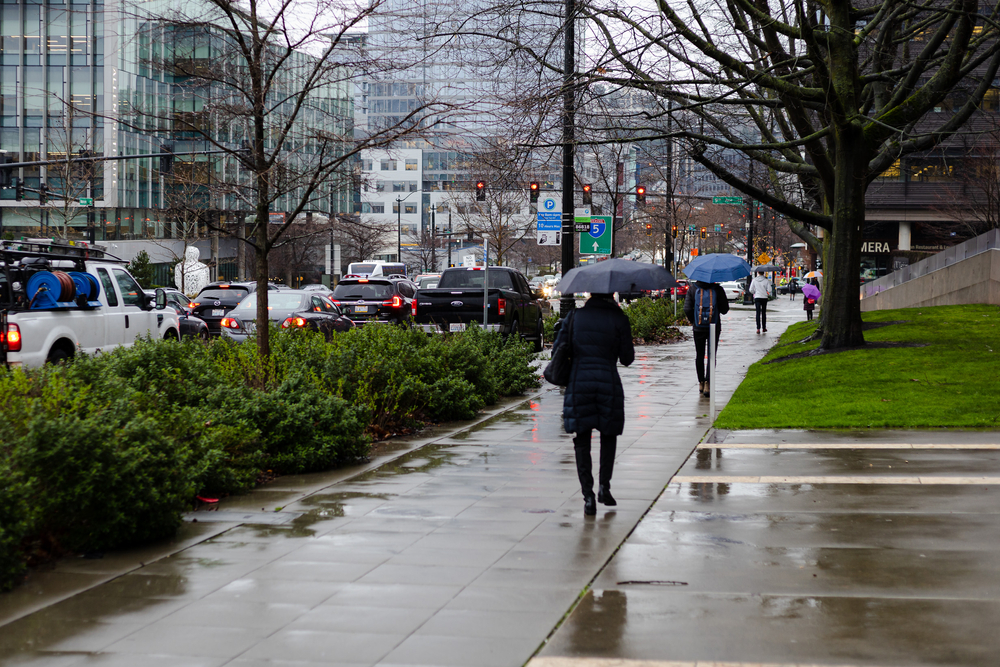 Pictured during the least busy time to visit Seattle, people walking along the street with umbrellas in the rain