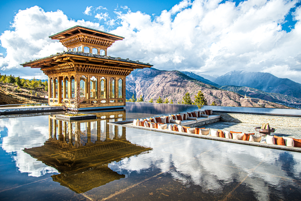Thimphu resting area by the pool with a bench seat sunk inside of the water pool next to a temple overlooking the valley below for a piece titled the best time to visit Bhutan