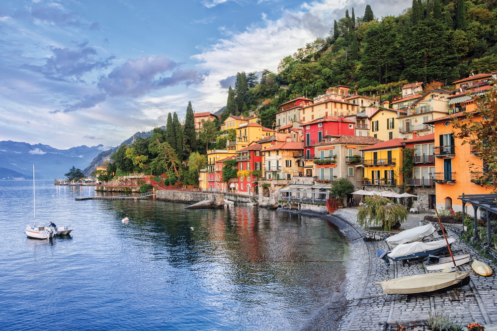 Dock view of the town of Menaggio with boats covered up and blue skies overhead during the overall best time to visit Lake Como