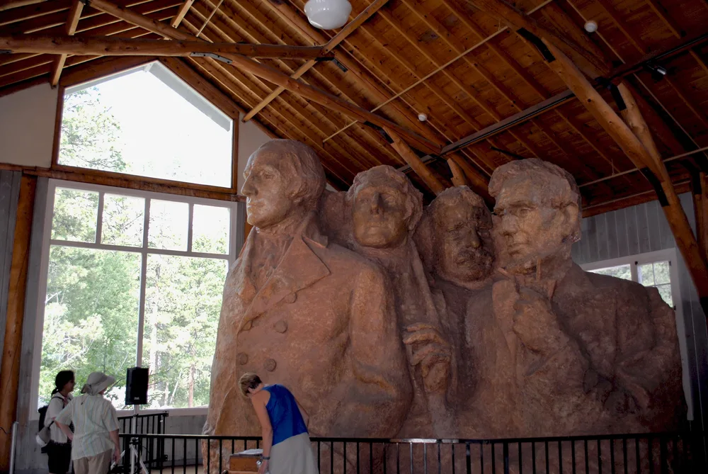 Indoor plaster mockup of the unique bust of the four presidents pictured during the overall best time to visit Mount Rushmore, the summer