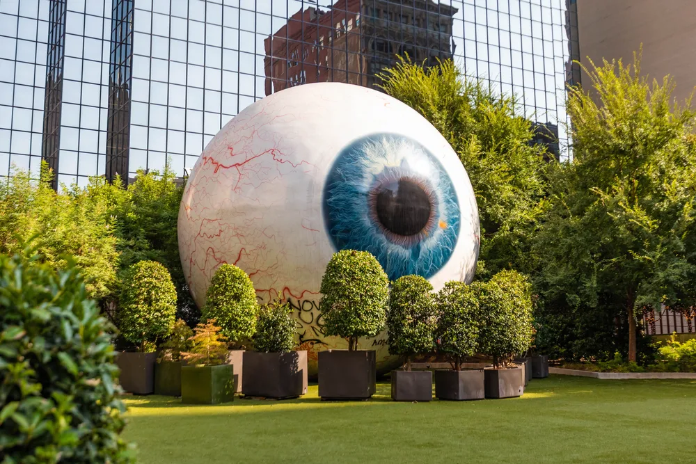 For a guide to the various times to visit Dallas and what each one has to offer, a giant eyeball pictured in the middle of downtown, surrounded by trees during the best time to visit the city