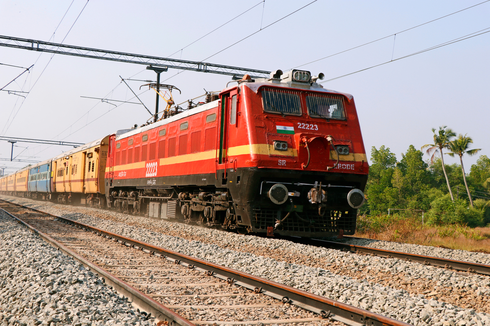 Photo of a red and yellow train making its way down the tracks in Kochi on a clear winter day during the best time to visit Kerala