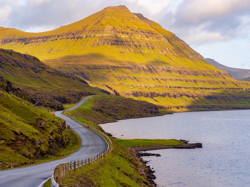 Photo of a narrow road winding down the coastline during the least busy time to visit the Faroe Islands