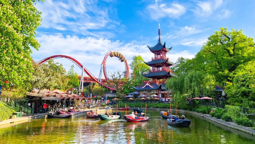 The third oldest amusement park in the world, Tivoli Gardens, pictured in the summer, the overall best time to visit Denmark, with gorgeous blue sky above