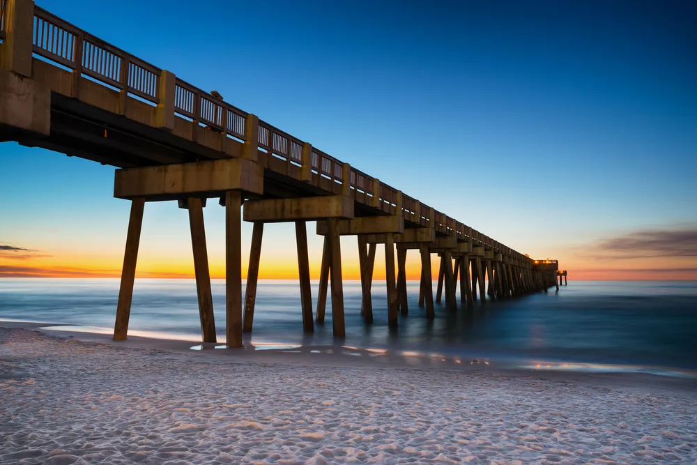 Pier pictured at dusk with still foggy water on a clear summer day, the overall best time to visit Panama City Beach