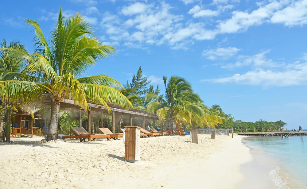 Completely empty Mahogany Beach below blue skies with clouds overhead during the least busy time to visit Roatan