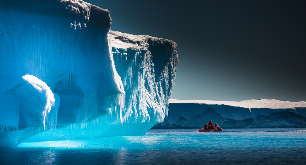 Scientists explore a glacier from a red boat during the overall best time to visit Antarctica