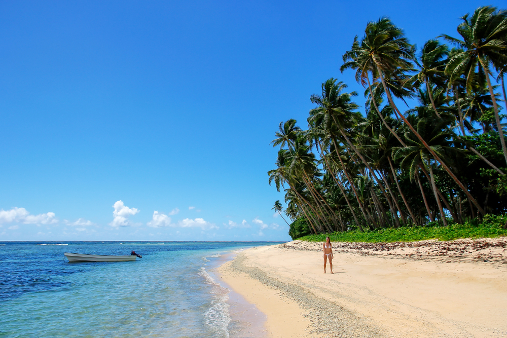 Gorgeous Asian woman walking along the beach on Taveuni Island during the overall best time to visit Fiji