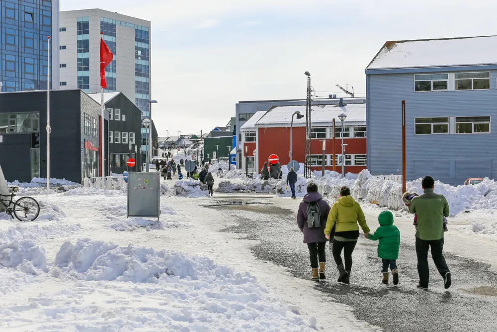 People walking around the city of Nuuk in the middle of winter, the overall worst time to visit Greenland, with snow all around