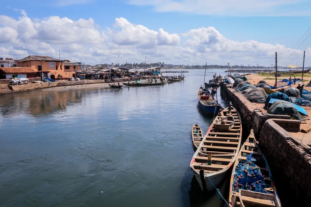 View of boats floating on the water outside Elmina port with clouds overhead