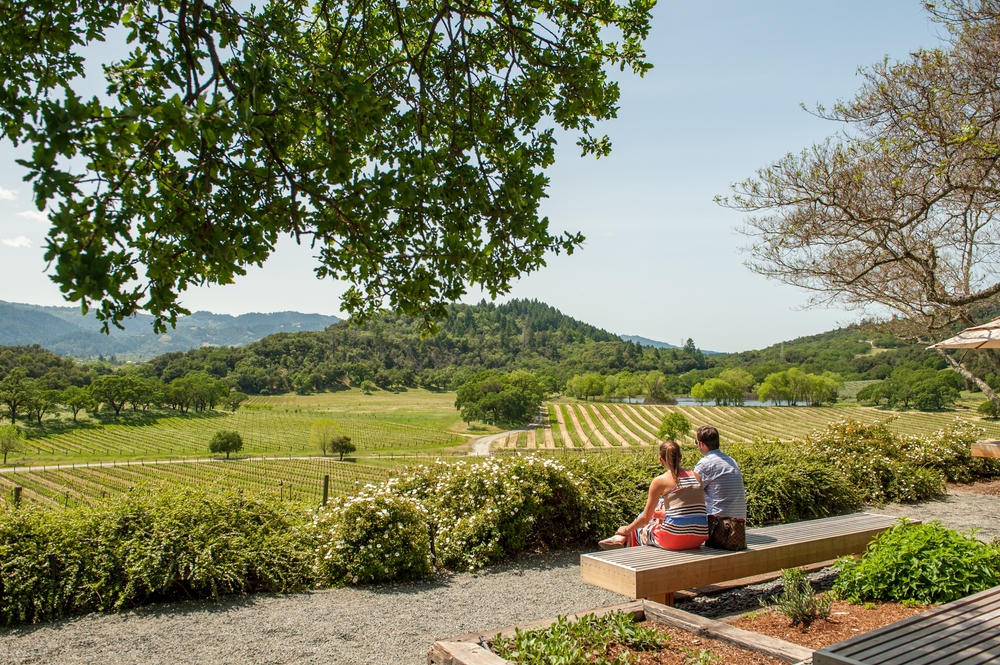 Photo of two people sitting on a bench overlooking the valley below for a piece titled What's the Best Time to visit Napa?