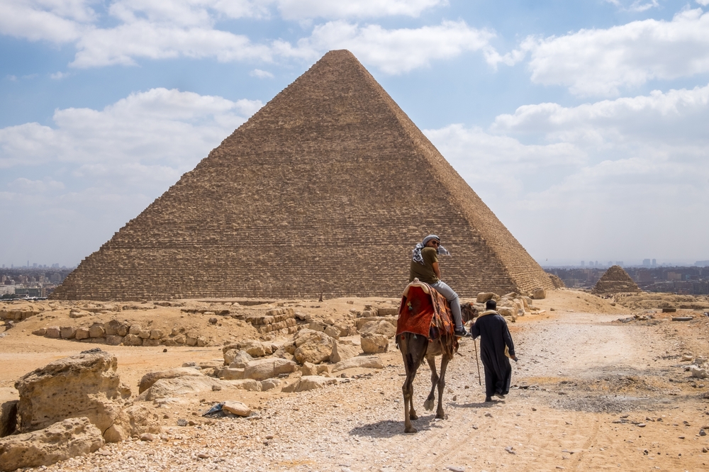 People riding camels around the Great Pyramids of Giza in April, one of the overall cheapest times to visit Egypt