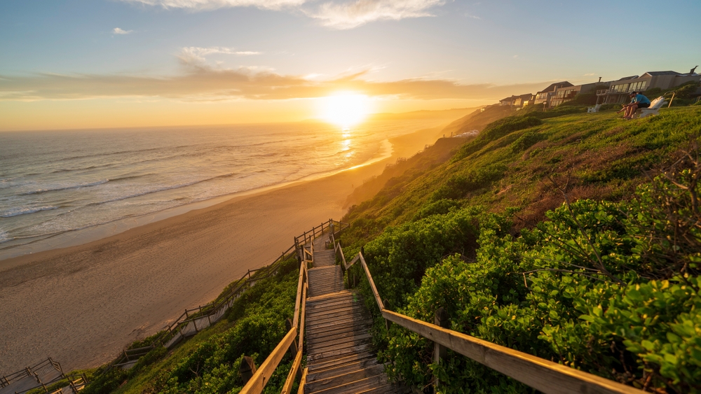 Sunset on Wilderness Beach with a gorgeous sunset over the bluffs and sand pictured for a guide to the best time to visit South Africa