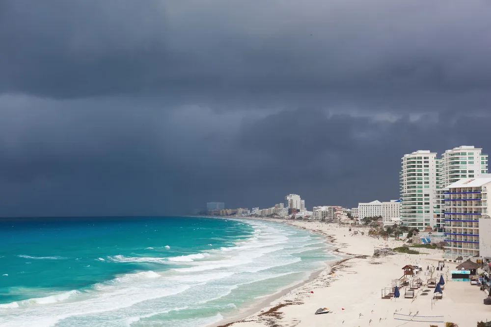 Storm clouds above the beach and long strip of hotels in Cancun during September, the worst time to visit the Caribbean