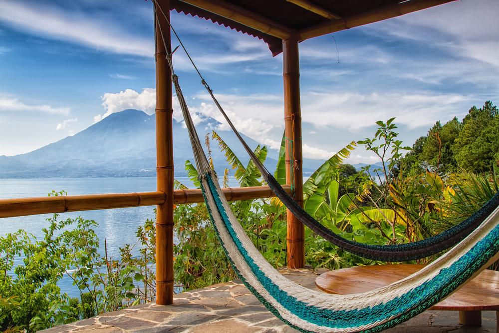 Hammocks in the foreground with Volcan San Pedro pictured with a few clouds over it during the best time time to visit Guatemala