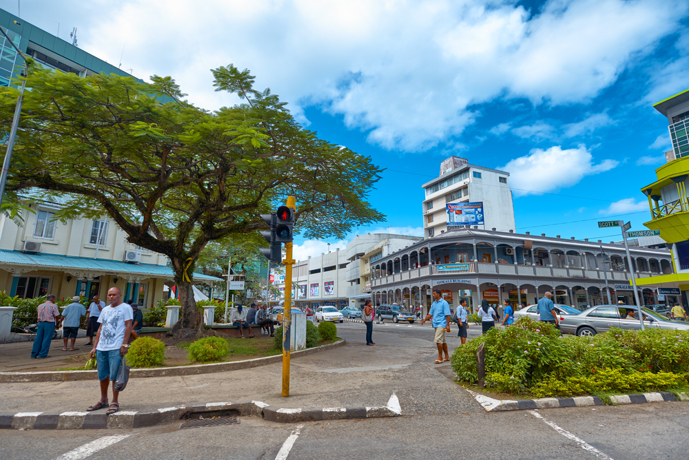 People walking through a street with a parking garage and shopping area in May, the least busy time to visit Fiji