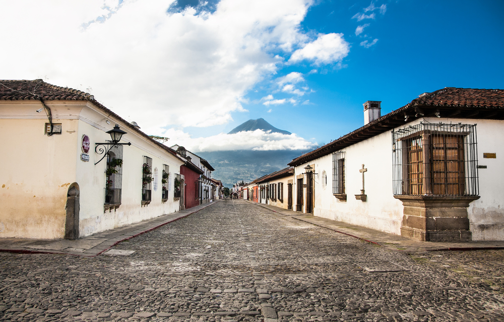 Neat cobblestone street in Antigua, Guatemala during the least busy time to visit with the giant volcano in the background