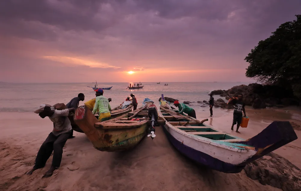 People pushing boats out to sea at dusk in Ghana during the overall best time to visit