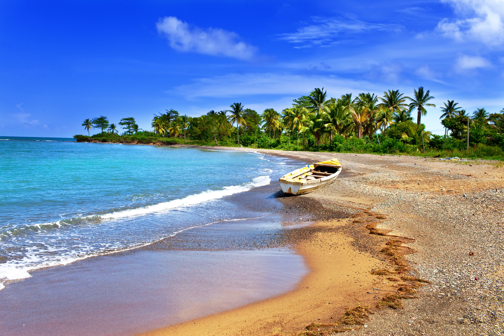 Sandy and rocky beach in Jamaica pictured during the overall least busy time to visit the Caribbean with a lone boat and nobody around