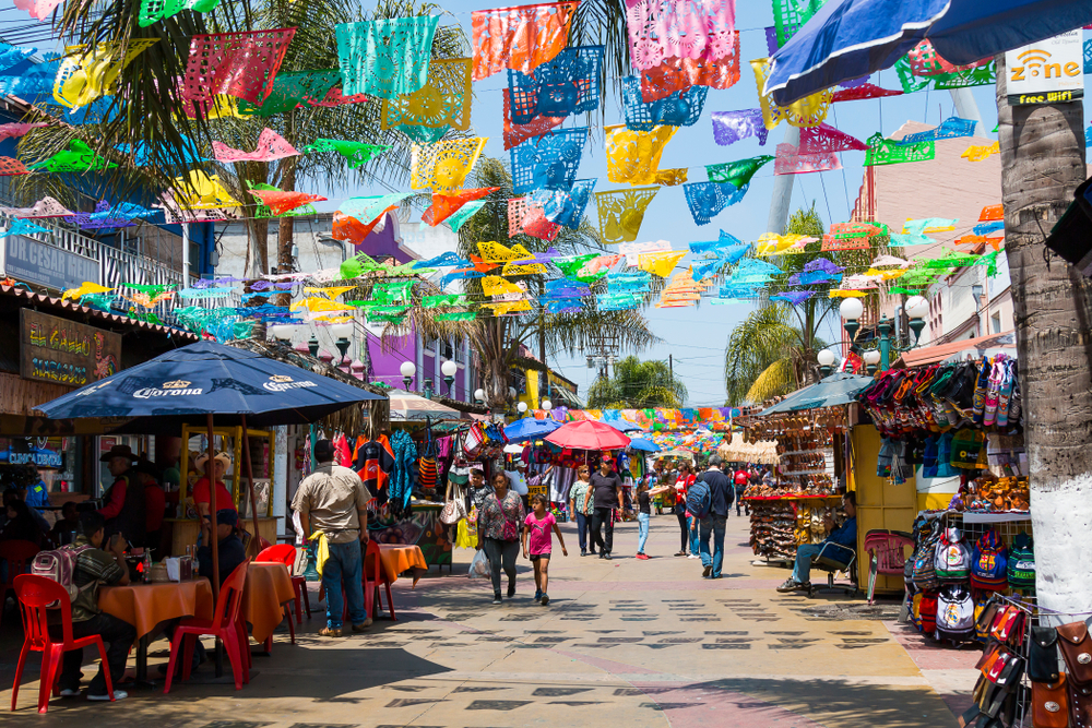 Photo of a shopping center below colorful flags in Tijuana, pictured during the summer, the worst time to visit