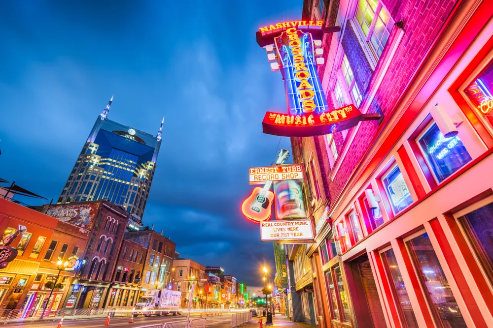Photo of a street in Nashville with lots of bars with neon signs pictured for a guide titled Is Nashville Safe to Visit