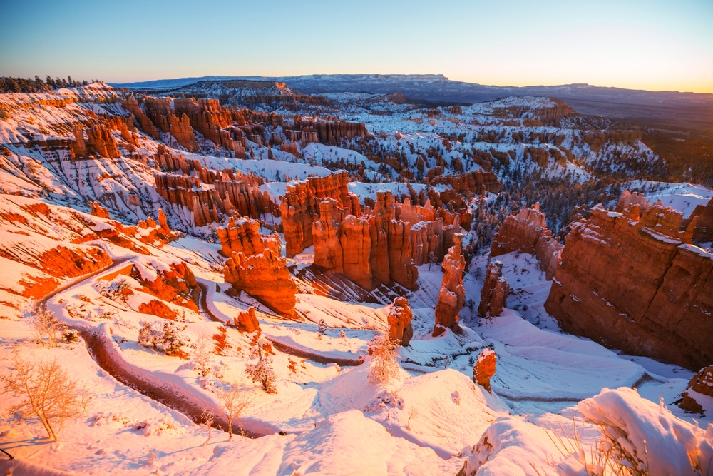 Picturesque colorful pink rocks seen with snow on them and the ground pictured during the cheapest time to visit Bryce Canyon