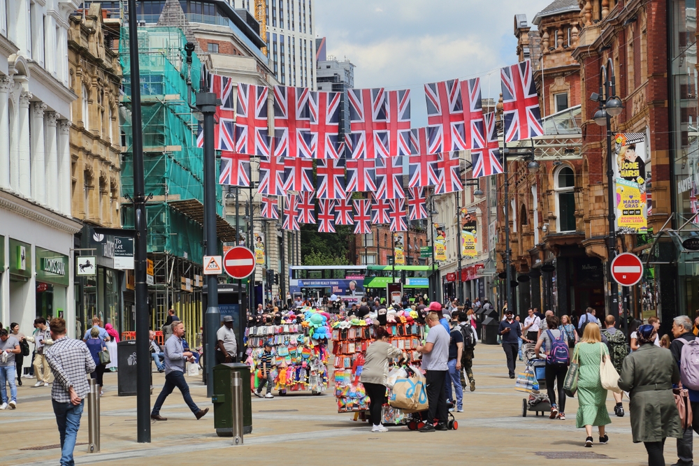 Photo of a bunch of flags above the walkway of an open-air shopping center pictured in Leeds during the best time to visit the United Kingdom