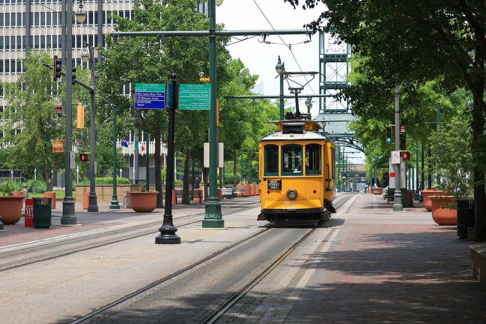 Yellow electric trolley making its way down the street in Memphis during the summer