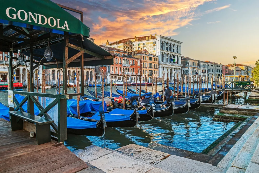 Neat gondola parking pictured in the late afternoon with boats floating on the water under a "gondola" sign, seen during the best time to visit Venice