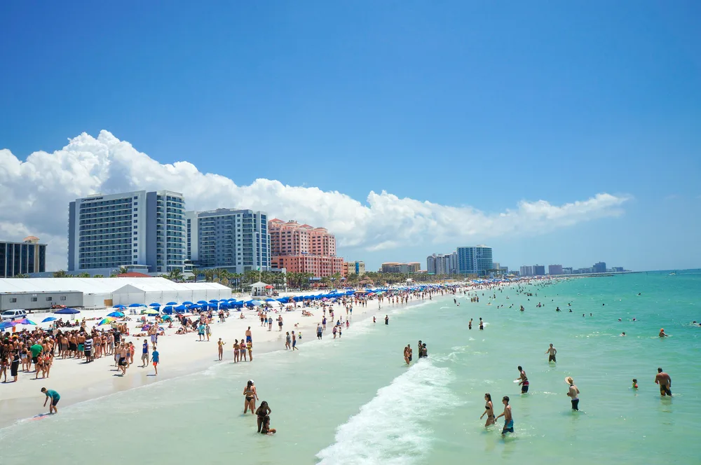 People on a beach in Clearwater during the best time to visit under blue sky in the spring with waves lapping the coast