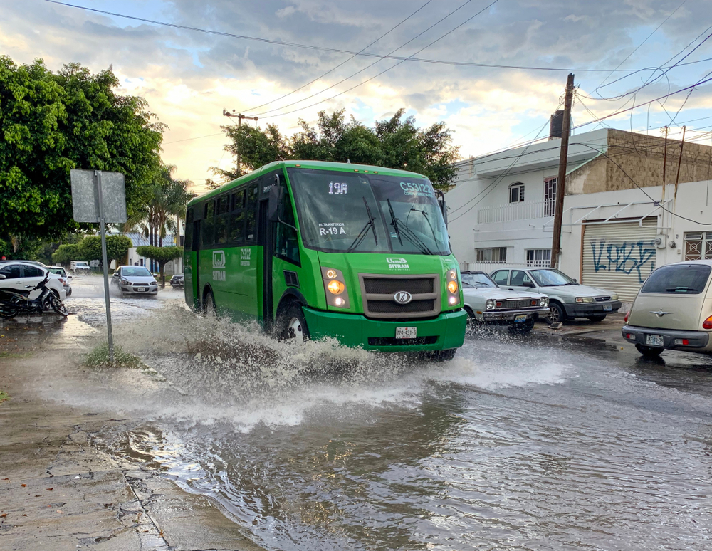 Bus driving through deep puddles in the middle of the street in Guadalajara for a guide to the best time to visit Mexico