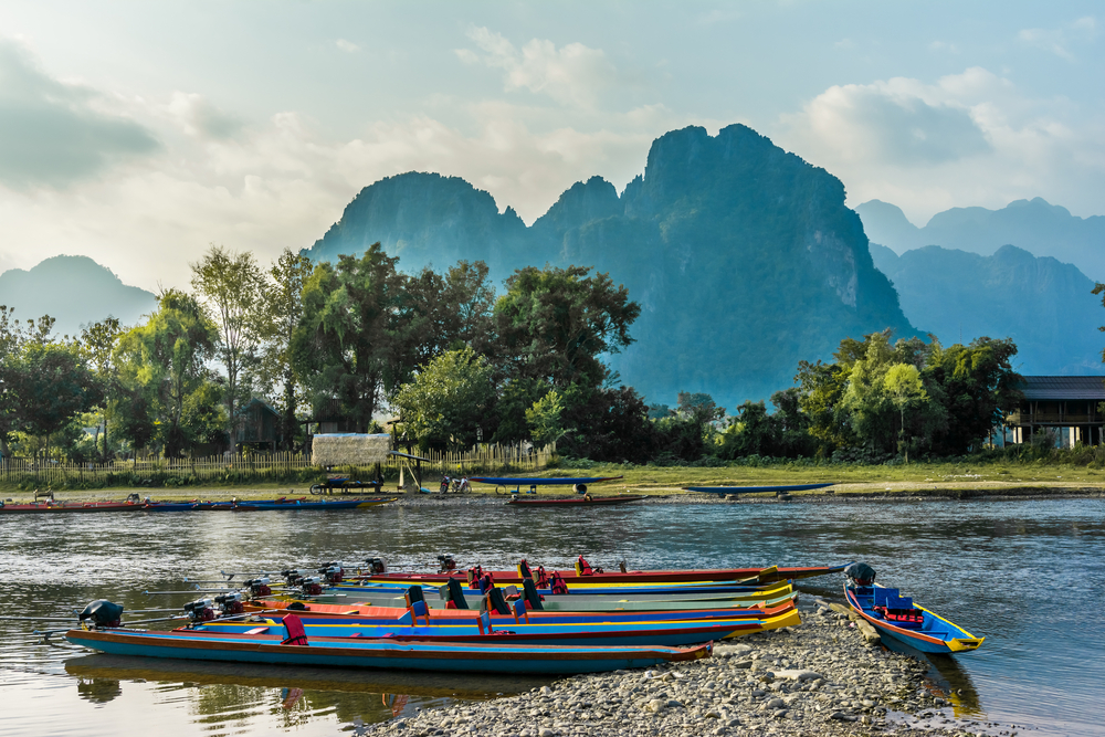 Boats pictured floating on the water of the Nam Song River in Vang Vieng during the best time to visit Laos