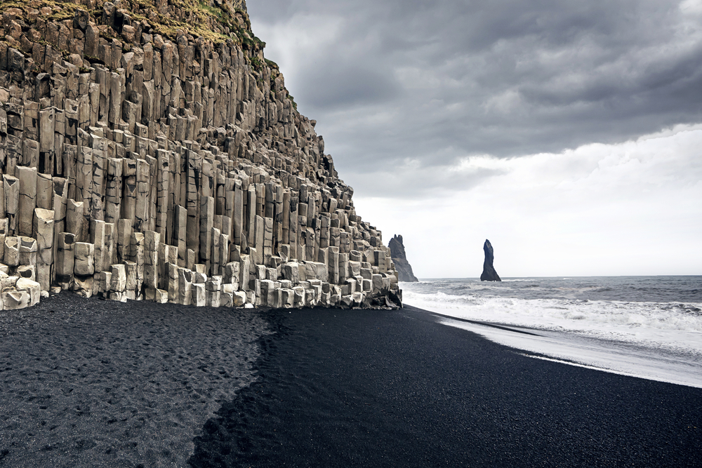 Gloomy day on the black sand beach of Reynisfjara with a neat rock formation on the left side of the image