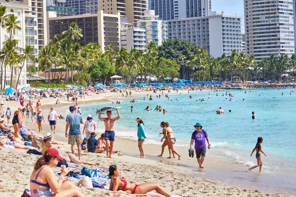 Photo of a bunch of people on the beach, seen during the winter, the worst time to visit Oahu