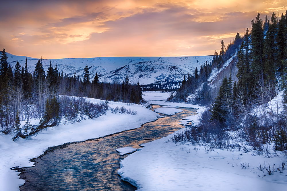 Dramatic sunset over the clear waters of the Phelan Creek, seen in the winter, one of the worst times to visit Alaska