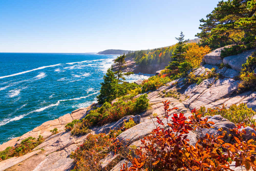 Picturesque view of the coastline of Acadia National Park pictured under blue skies during the fall, one of the very best times to visit NEw England