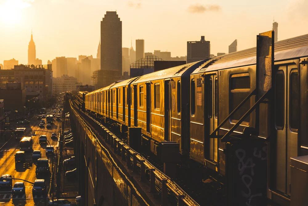 Elevated subway cars pictured in front of a beautiful dusk skyline during the overall best time to visit New York City