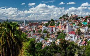 Aerial view of the capital city, Antananarivo, and its colorful French Colonial buildings with clouds overhead and lush rainforest around during the best time to visit Madagascar