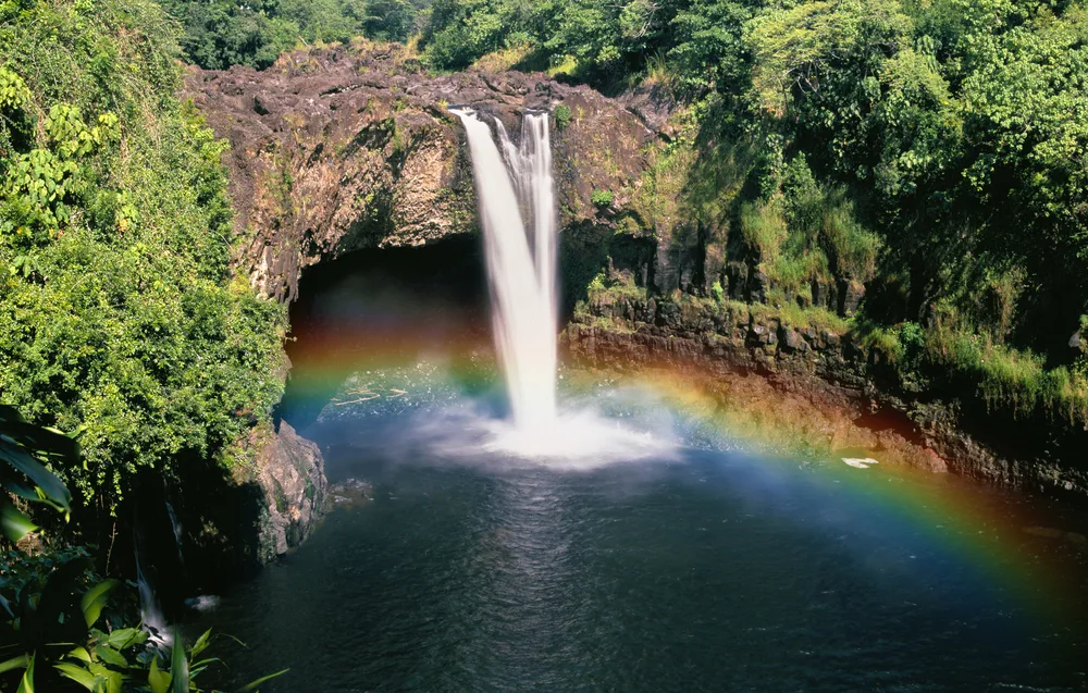 Stunning Wailua Waterfall with a rainbow forming in its mist outside of Lihue on Kauai, Hawaii during the cheapest time to visit Hawaii 