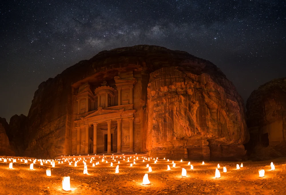 Rock building in Petra illuminated by hundreds of candles on the ground at night for a section showing the weather, prices, and crowd conditions by month in Petra