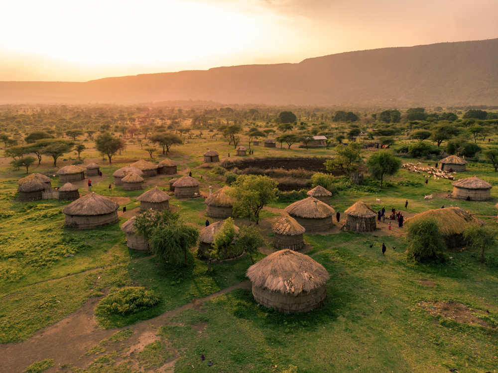 Aerial view of dozens of African huts in a traditional Maasai village at sunset for a frequently asked questions section on the best months to visit Kenya