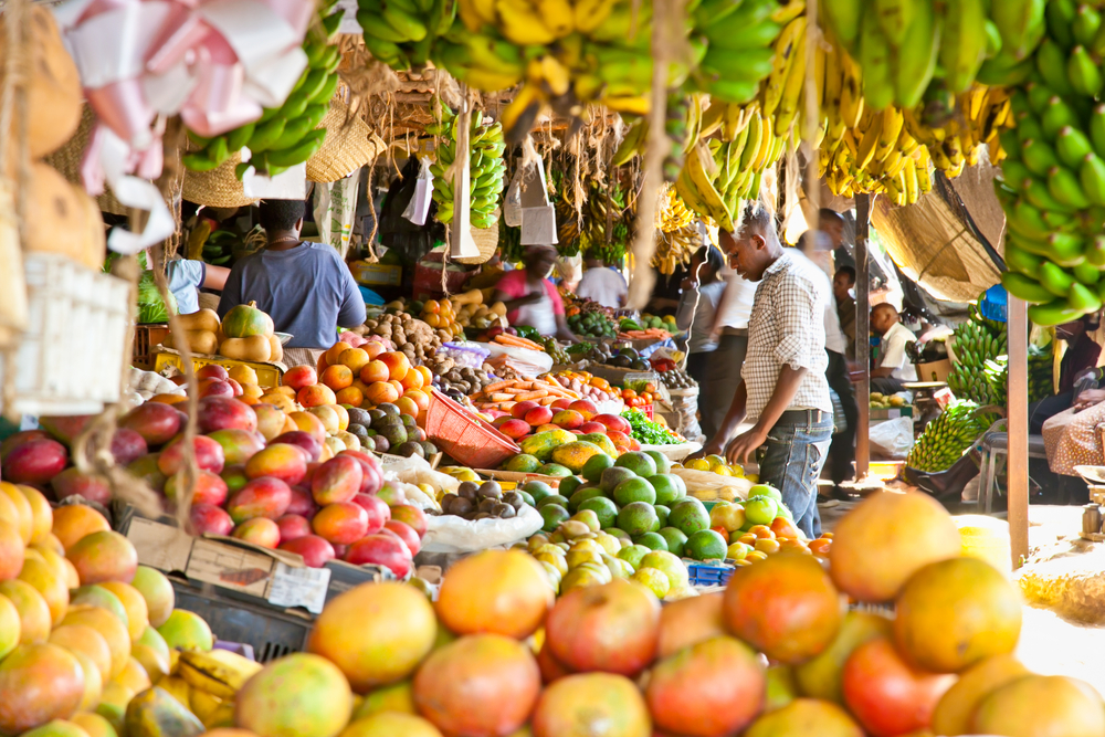 Fruit and vegetables stacked up for sale at a fresh market in Nairobi as people browse in the background for a post showing the overall best and worst time to visit Kenya