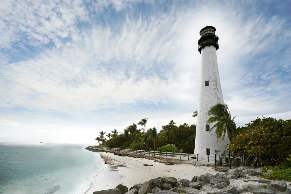 View of the Cape Florida Lighthouse in Bill Baggs Cape Florida State Park on a cloudy day during the worst time to visit Miami for a guide detailing the best and worst months to visit the city