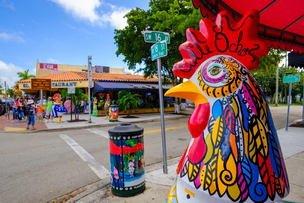Colorful rooster and street art in Little Havana with cafes and shops around during the cheapest time to visit Miami with sunny skies overhead