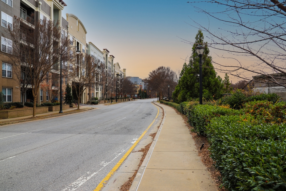 Long winding road seen during the least busy time to visit Georgia featuring crisp green trees lining a road and the downtown skyline