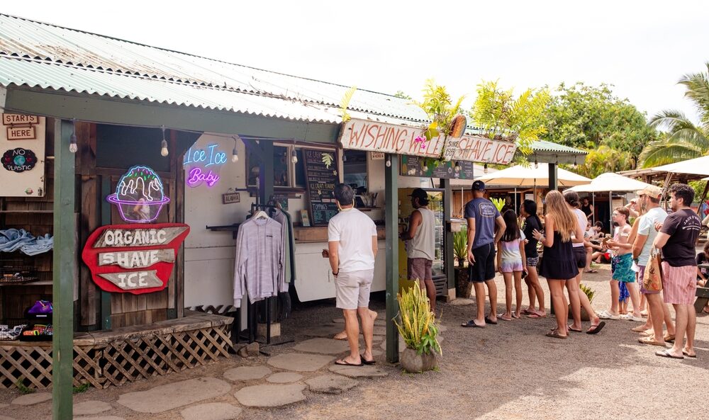 View of people outside of a Hanalei Food Truck Court eating shave ice