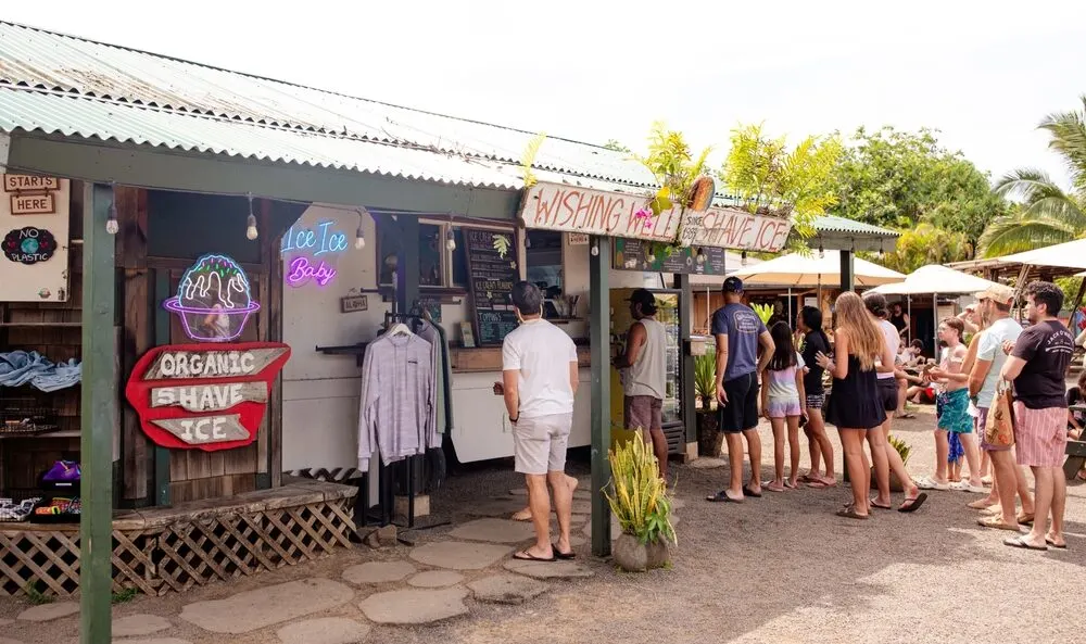 View of people outside of a Hanalei Food Truck Court eating shave ice